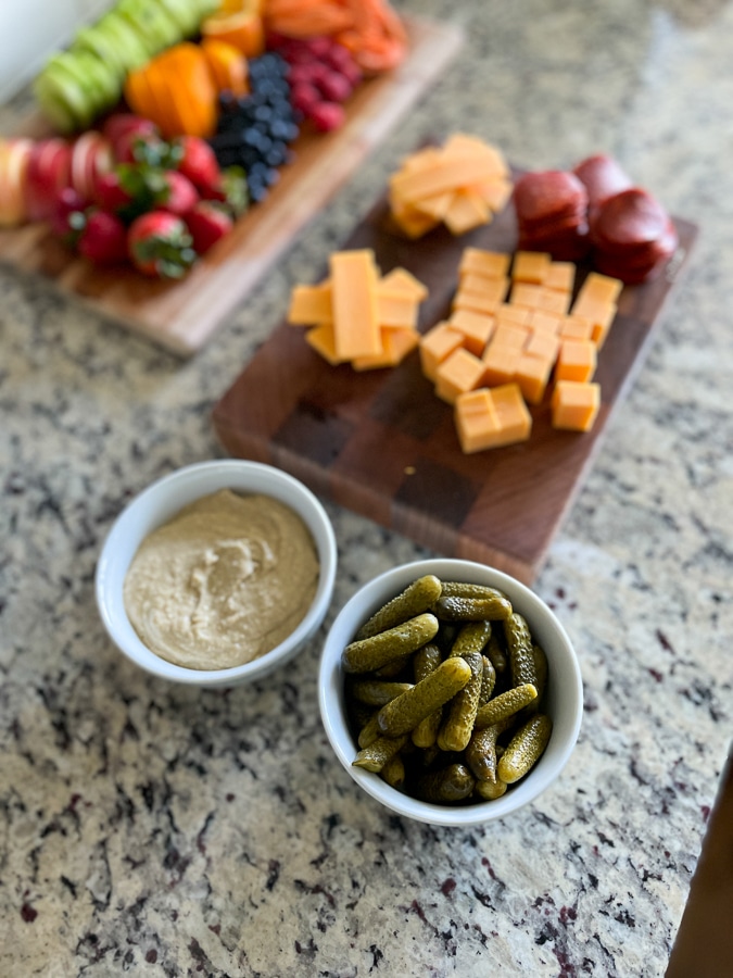 Kids Charcuterie Board prep with cheese, pickles and hummus in bowls