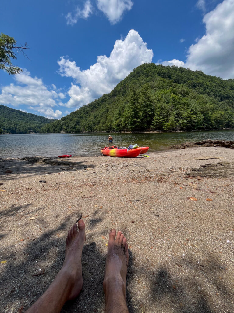 Kath Eats Blogger Kath Younger shares their Bear Lake Reserve vacation: in photo: feet on the sand with a view of the lake